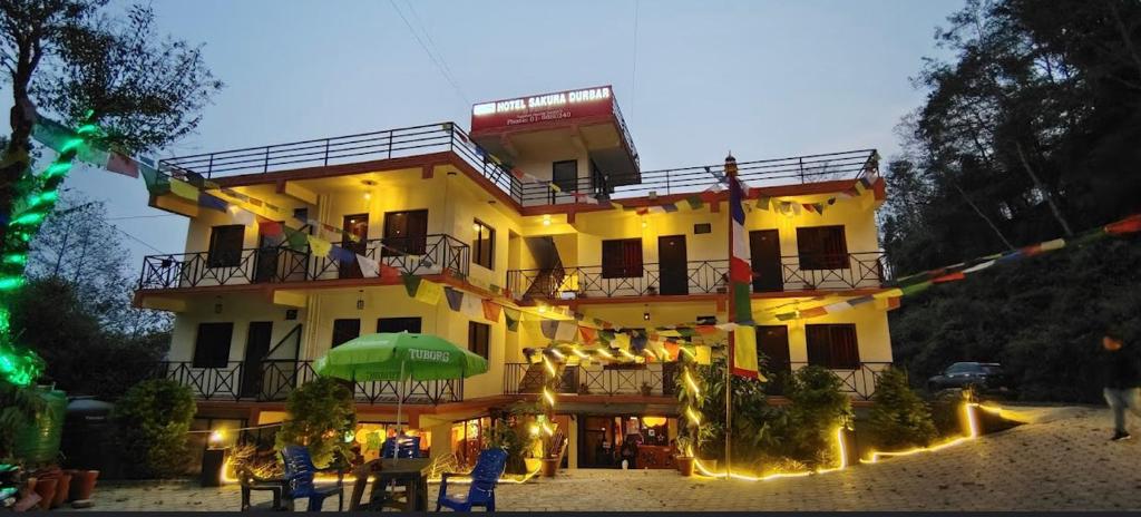 a large yellow building with people sitting on the balcony at Hotel Sakura Durbar in Nagarkot