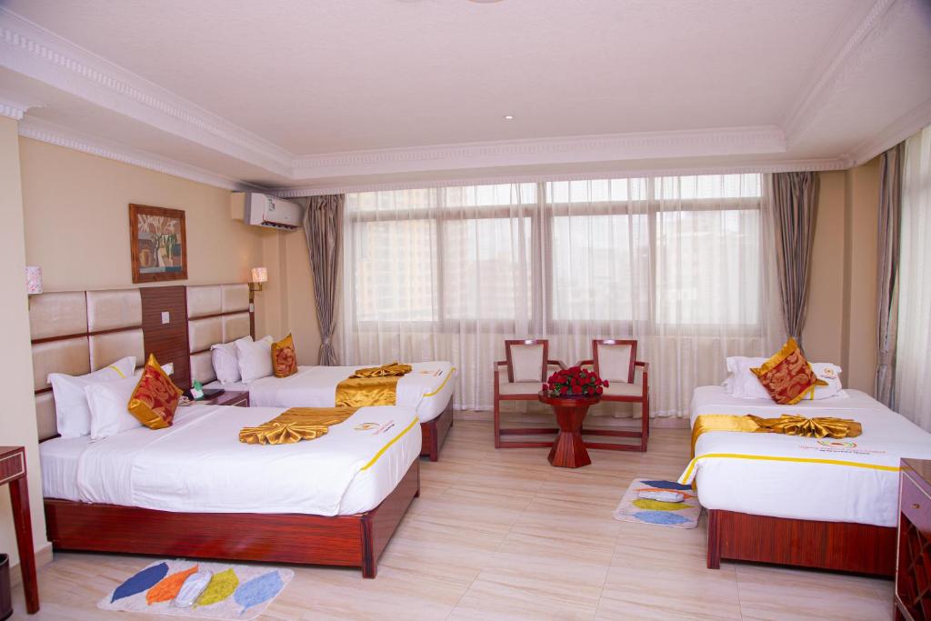 a hotel room with three beds and a window at Tiffany Diamond Hotels Ltd - Indira Gandhi street in Dar es Salaam