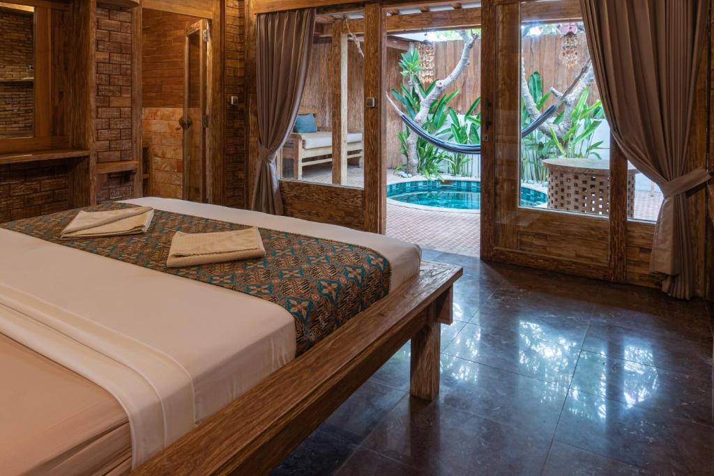 a bedroom with a bed and a view of a pool at Jawa House Private Villas in Gili Trawangan