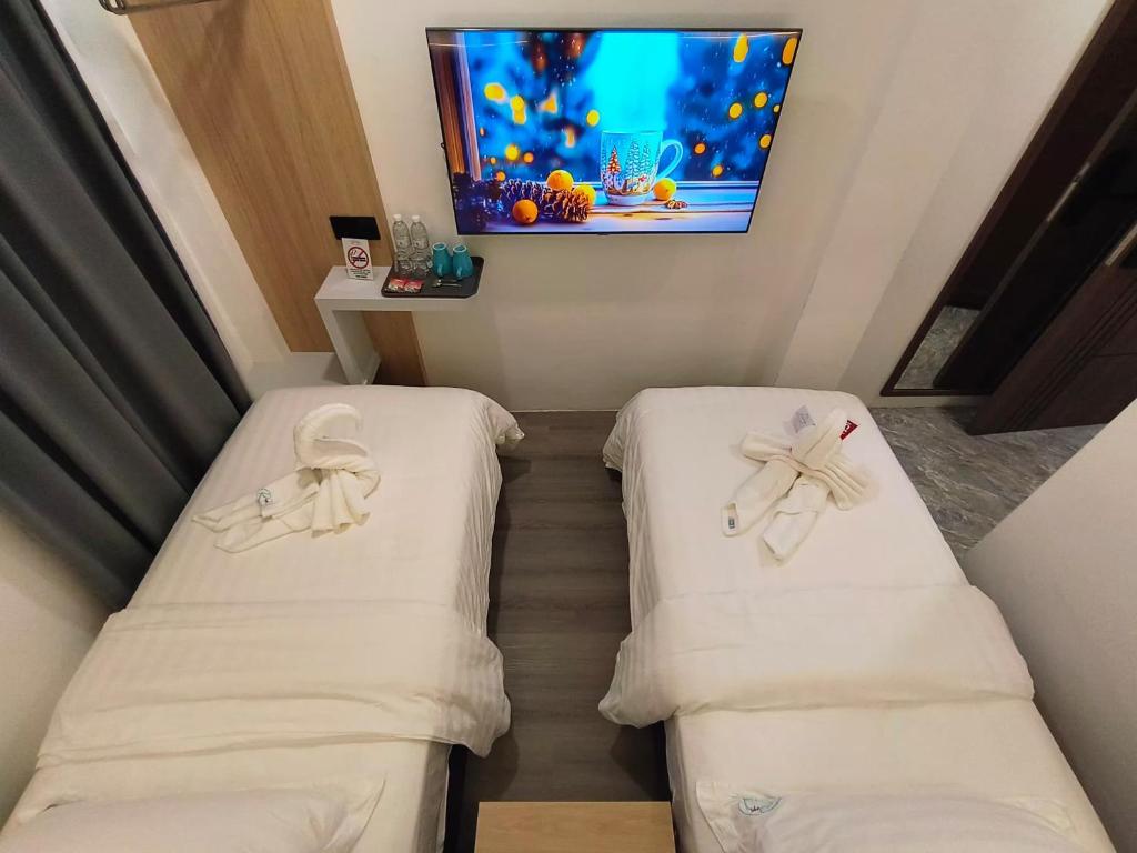 duas camas num quarto com uma televisão na parede em Red's Hotel em Bintulu