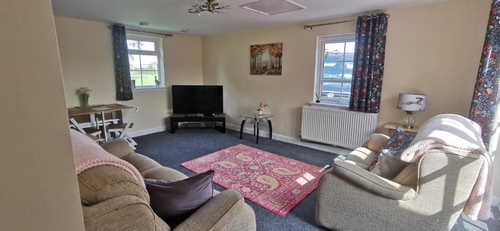 a living room with two couches and a flat screen tv at The Wee Hoose in Dumfries