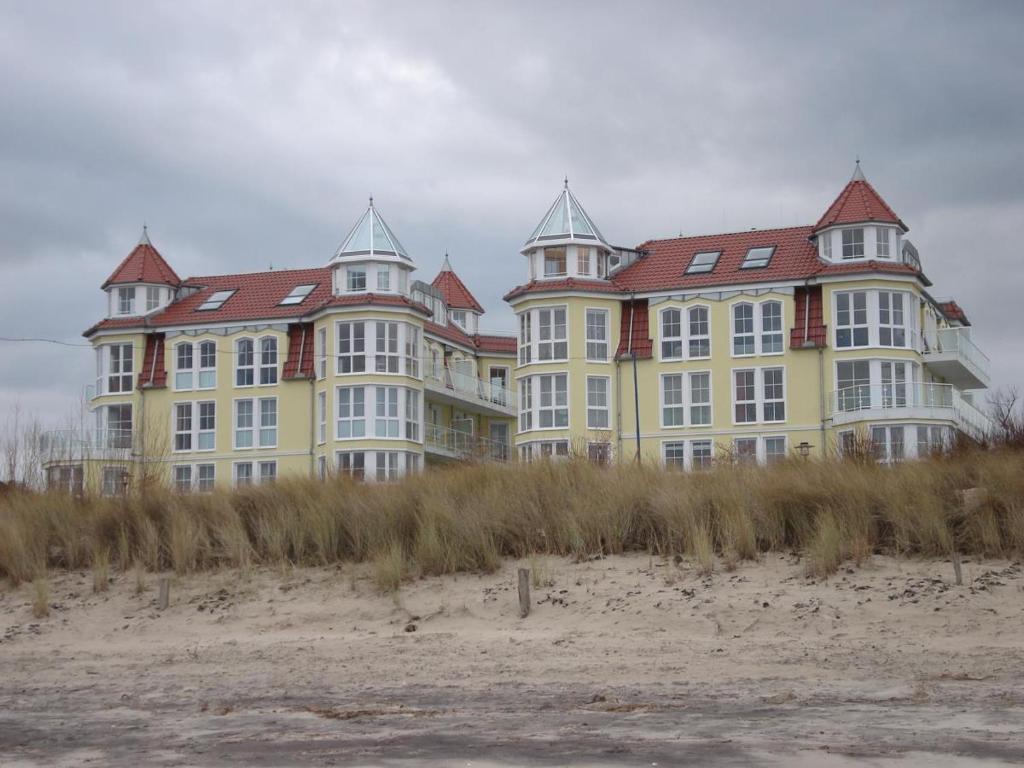 un grand bâtiment jaune avec des toits rouges sur la plage dans l'établissement Schönes Appartm. mit Südbalkon, Blick auf Schloonsee, Tiefgarage, à Bansin