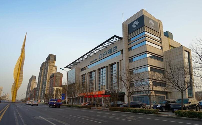 un edificio con una torre de reloj al lado de una calle en Atour Hotel Tianjin Binhai Second Avenue Branch en Binhai