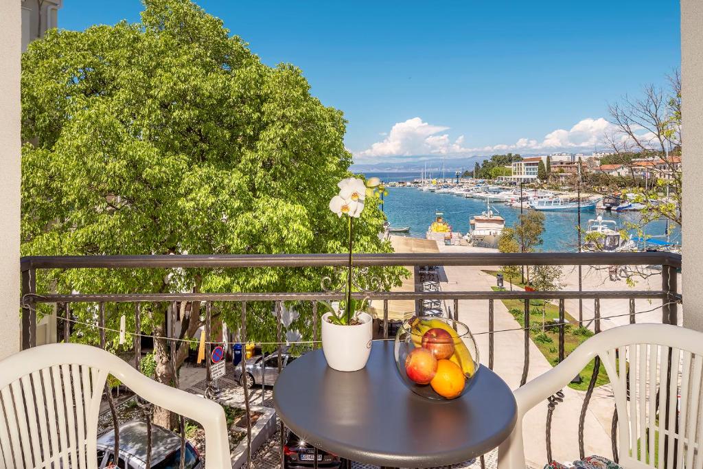 a table with fruit on a balcony with a view of a harbor at Apartment Dumica in Malinska
