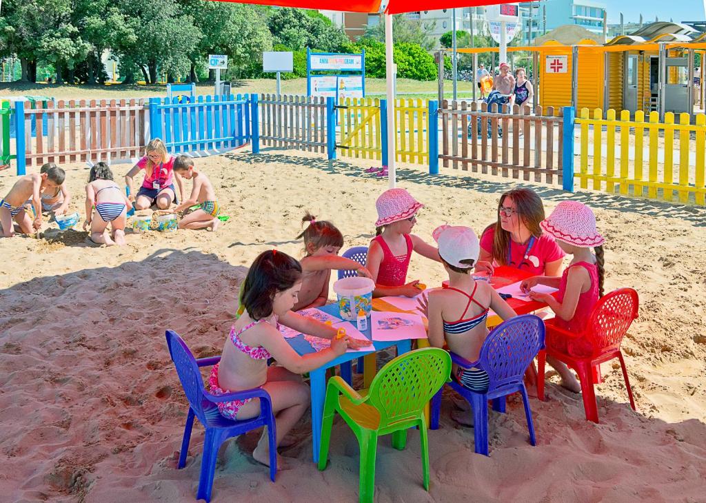a group of children sitting at a table in the sand at Hotel Montecarlo in Bibione