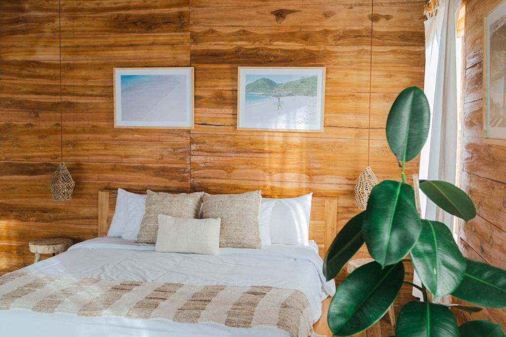 ein Schlafzimmer mit einem Bett und einer Holzwand in der Unterkunft Sangat Indah Wooden House Uluwatu in Uluwatu