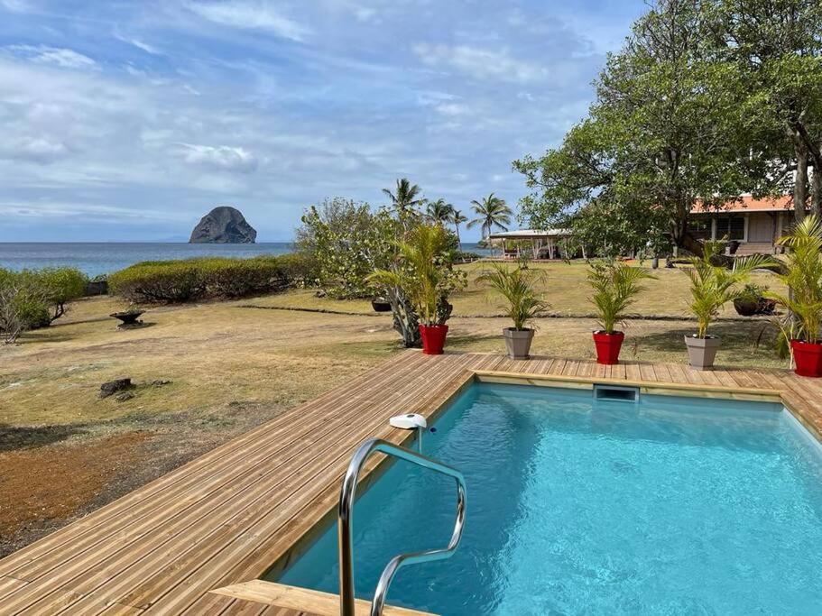 a pool with a wooden deck and a view of the ocean at Les Lauriers du Rocher 2 in Le Diamant