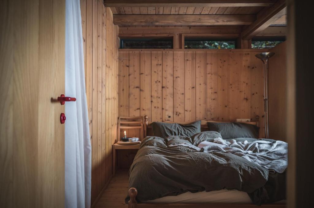 a bed in a room with a wooden wall at Bregenzerwald Ferienhaus in Egg