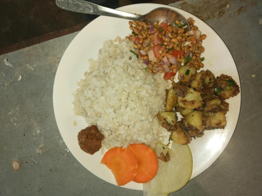 a plate of food with rice and vegetables and a spoon at Unique point home stay in Nagarkot