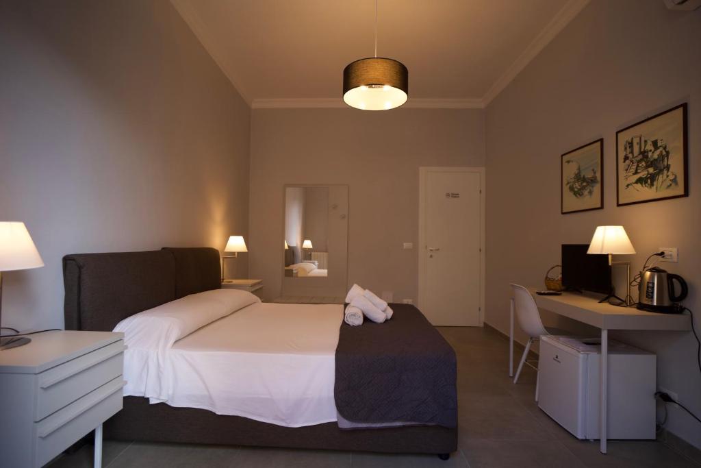 Donna Franca Rooms and Suite في باليرمو: غرفة نوم بسرير ومكتب وجهاز كمبيوتر