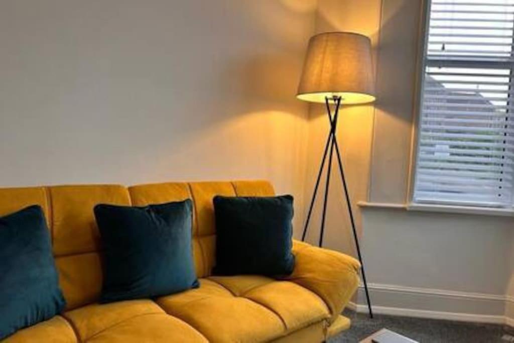 a living room with a yellow couch and a lamp at Cosy One Bedroom Apartment in Exeter