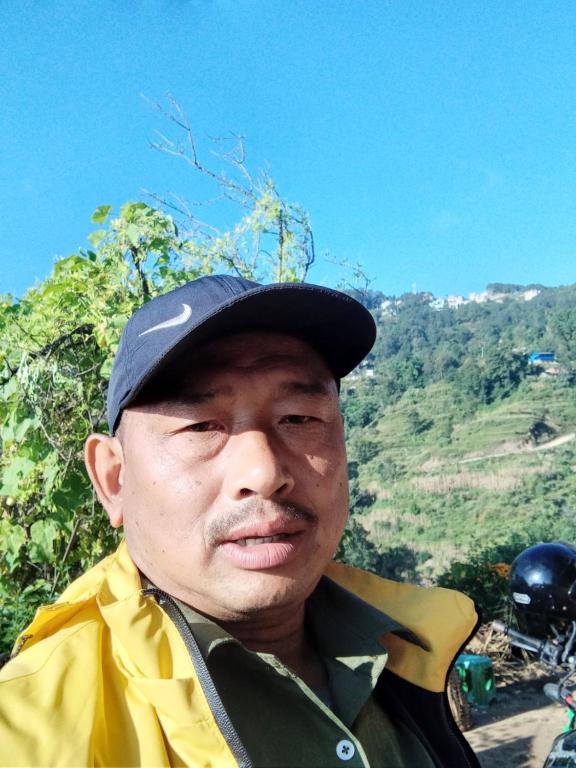 a man wearing a hat and a yellow jacket at Unique point home stay in Nagarkot
