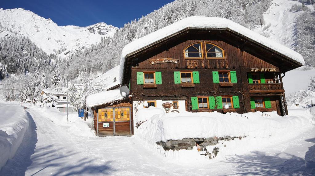a wooden house covered in snow in the mountains at Haus Älpele in Klösterle am Arlberg