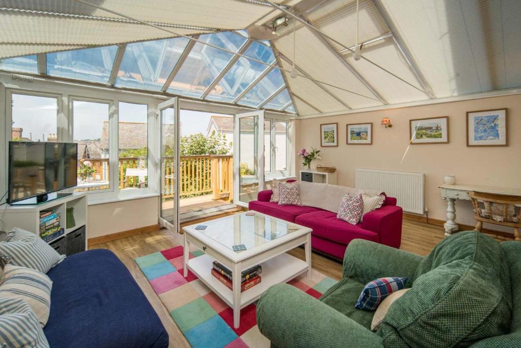 a living room with two couches and a tv at The Green House - 12 Kings Close in Bembridge