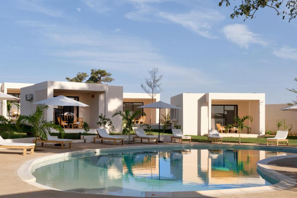 a villa with a swimming pool in front of a house at Kawga Hôtel in Ngaring