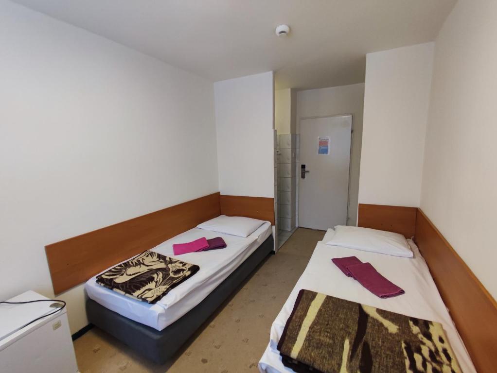 dwa łóżka w małym pokoju z różowymi elementami w obiekcie Jantar Economy w Szczecinie