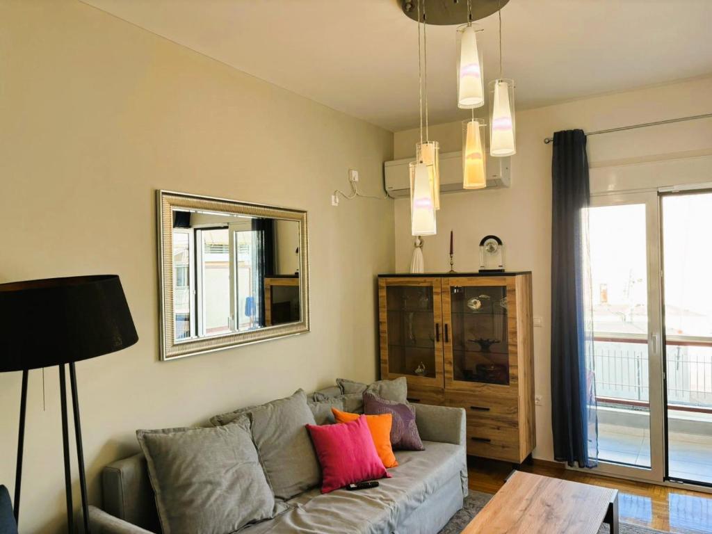 ein Wohnzimmer mit einem grauen Sofa und bunten Kissen in der Unterkunft Apartament Athina in Athen