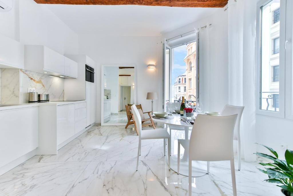 - une cuisine blanche et une salle à manger avec une table et des chaises dans l'établissement Alba apartment antibes street, by Welcome to Cannes, à Cannes