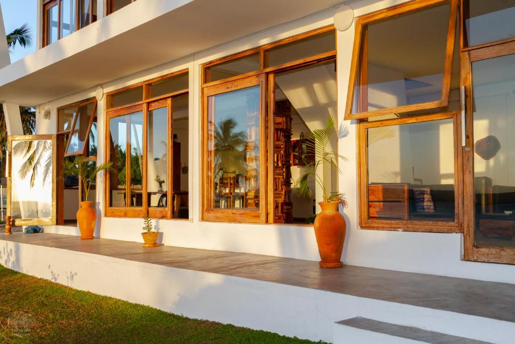una casa con grandes ventanas y jarrones en el porche en Canto das Amêijoas, en Inhambane