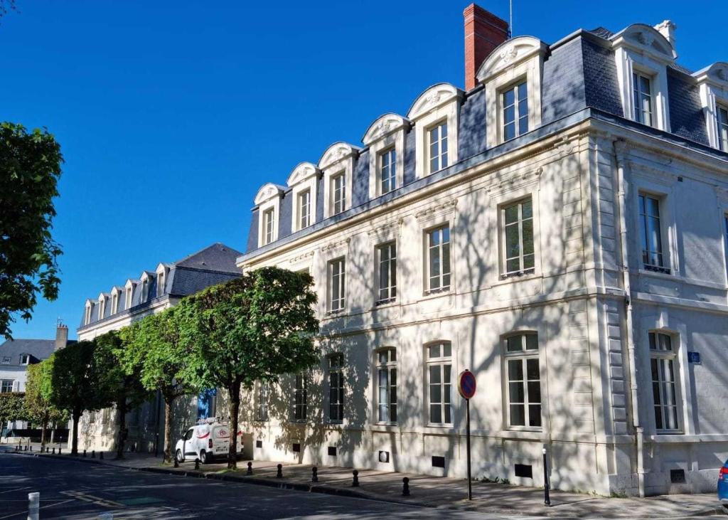 un grand bâtiment blanc au bord d'une rue dans l'établissement Résidence de Bourges, à Bourges