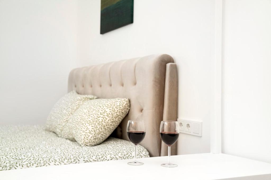 a bed with two glasses of wine on a table at Central Station Apartment No5 in Kaunas