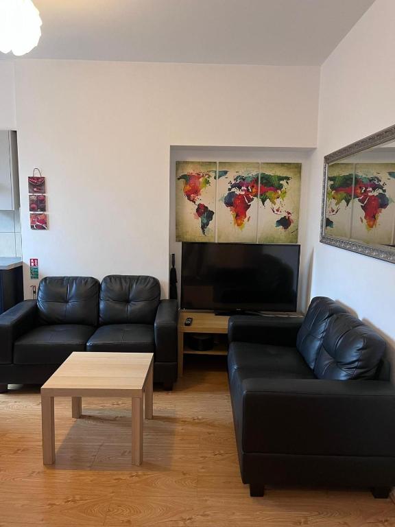 ein Wohnzimmer mit zwei schwarzen Sofas und einem Flachbild-TV in der Unterkunft Westend Villas in Leicester