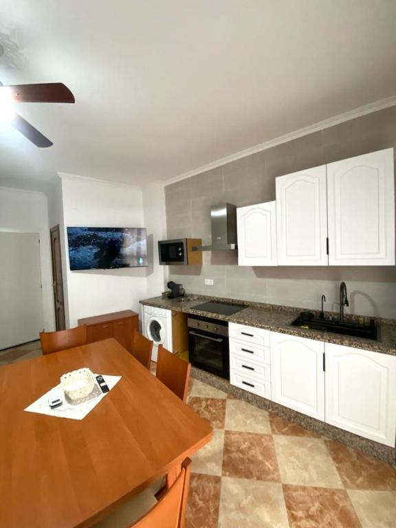 a kitchen with a wooden table and white cabinets at Casa Cruz de Marbella Luque in Luque