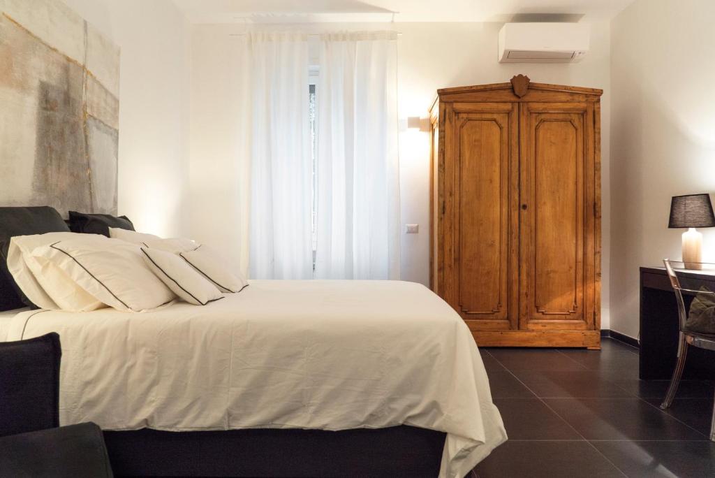 een slaapkamer met een wit bed en een houten kast bij Roma San Pietro - Le Grazie del Vaticano in Rome