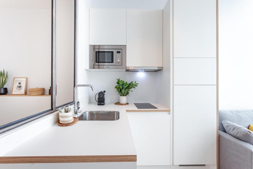 a white kitchen with a sink and a microwave at Les Appartements de Grenoble in Grenoble