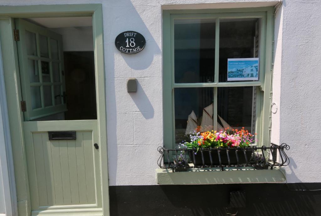 a window with a pot of flowers on a balcony at Drift Cottage - Fisherman's Cottage Brixham harbour in Brixham