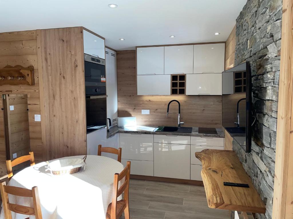 a kitchen with a table and a stone wall at Carène in Valloire