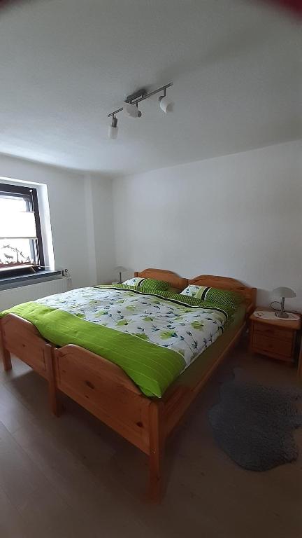 a bedroom with a wooden bed with a green comforter at Ferienwohnung am Querweg in Bockau