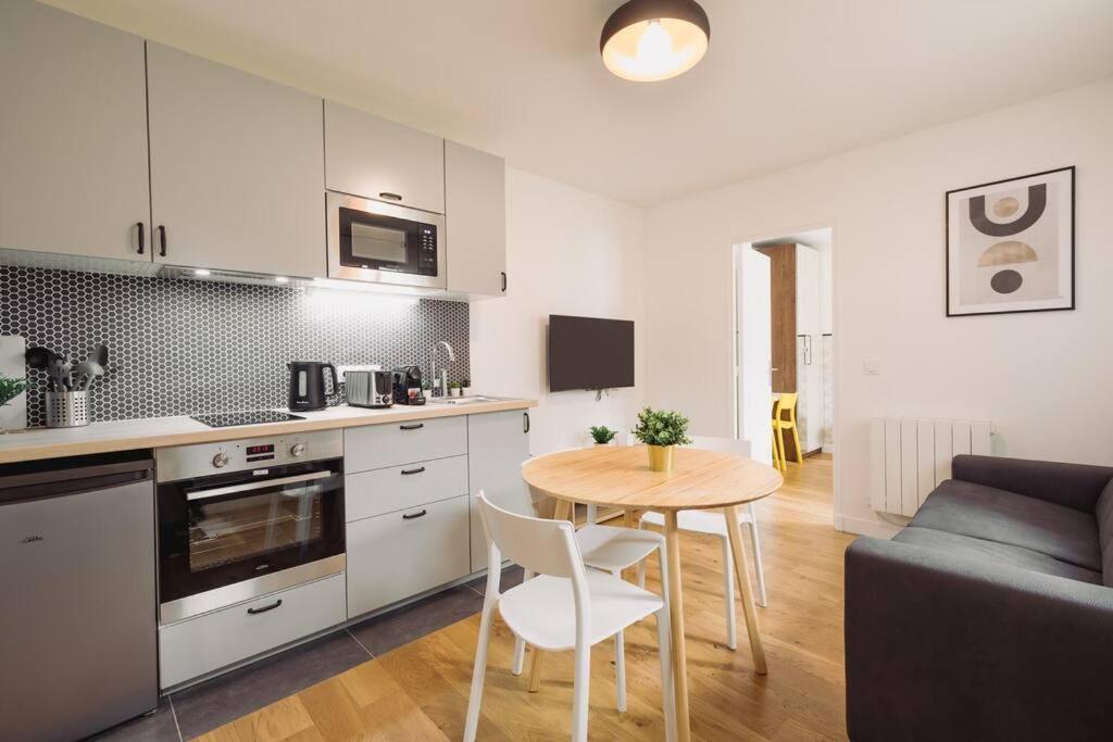 kuchnia i salon ze stołem i kanapą w obiekcie Lovely apartment for two-person w mieście Aubervilliers