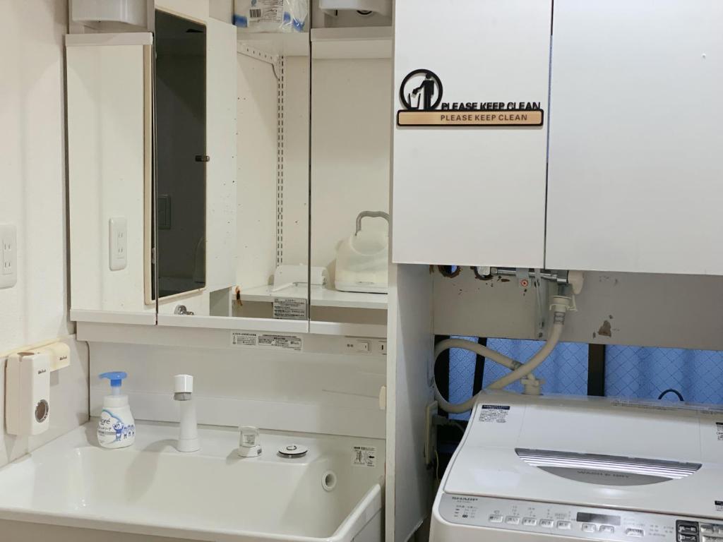 a white kitchen with a sink and a mirror at Asakusa Inn 屋上バルコニー付き100m2広々快適一棟ハウス in Tokyo
