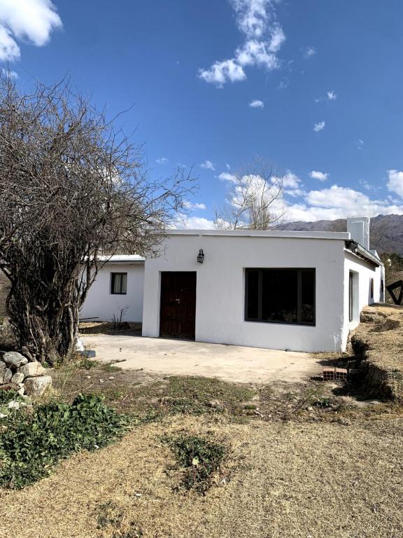een wit gebouw met een grote deur in een tuin bij Casa Los Membrillos in Tafí del Valle