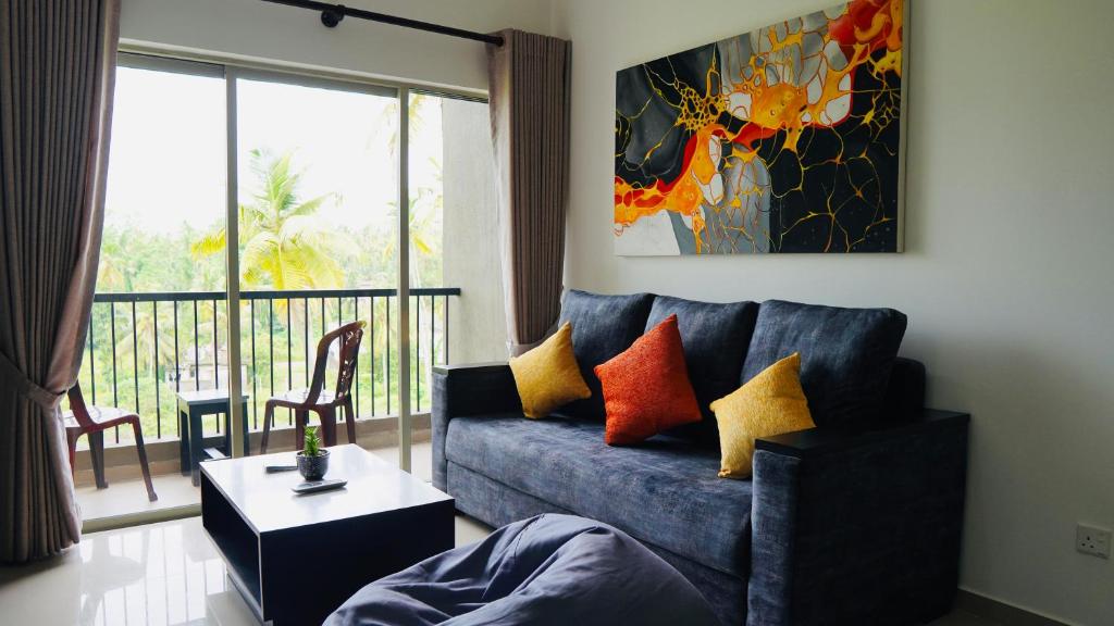 a living room with a blue couch and a balcony at Coco Nest Colombo Sri Lanka in Malabe
