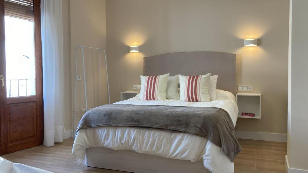 1 dormitorio con 1 cama grande con almohadas rojas y blancas en Ciudad del Encaje 1, en Almagro
