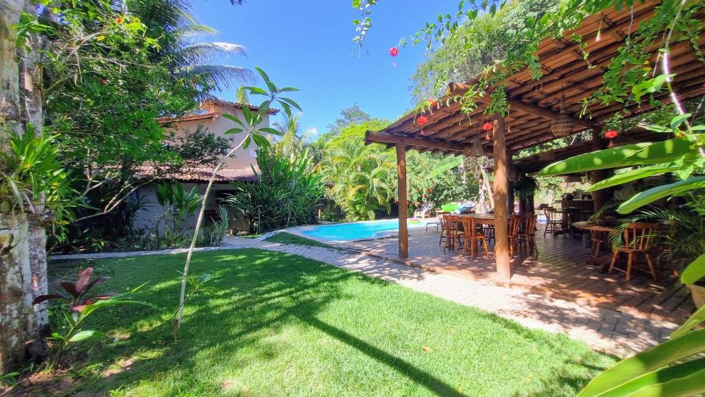 a backyard with a wooden pergola and a swimming pool at Vila Pitanga Trancoso in Trancoso
