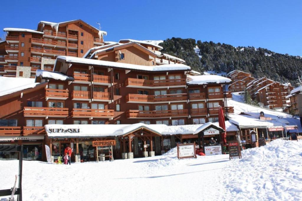 a large ski lodge with snow on the ground at Résidence Le Pralin in Les Allues