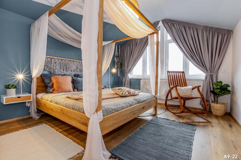 a bedroom with a canopy bed and a chair at KORZO LIPNO 2 in Lipno nad Vltavou