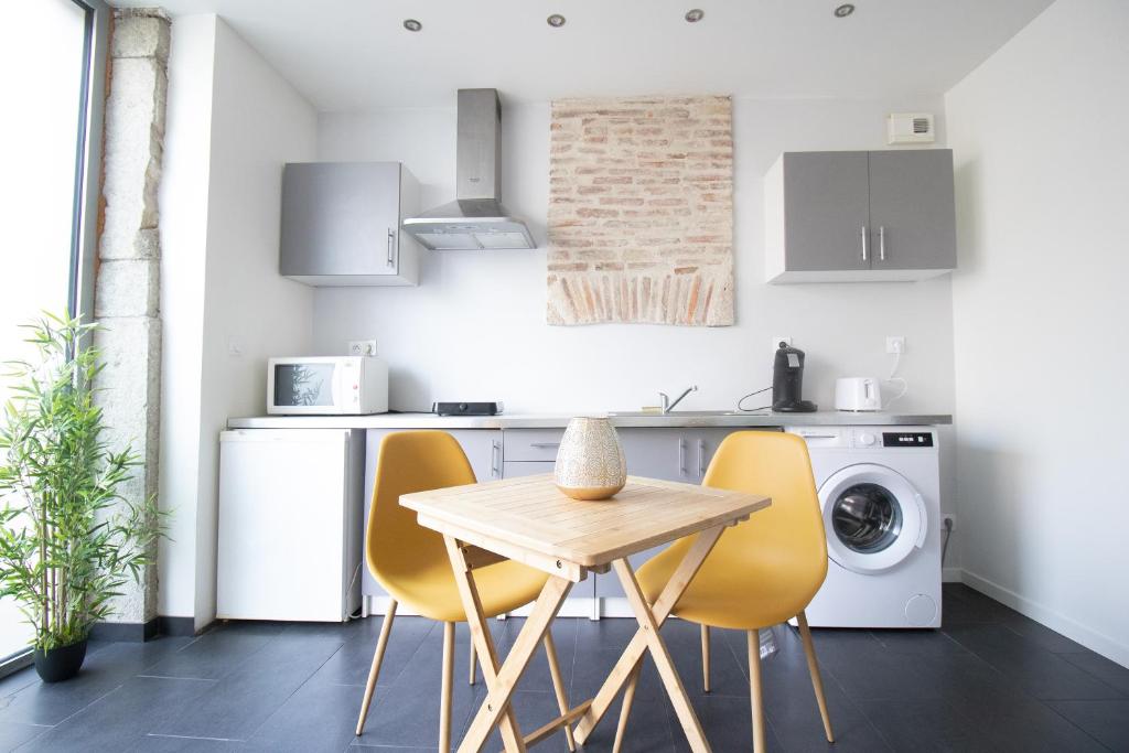 une cuisine avec une table et des chaises jaunes dans l'établissement Appartement T2 au centre de Bourg en Bresse, à Bourg-en-Bresse