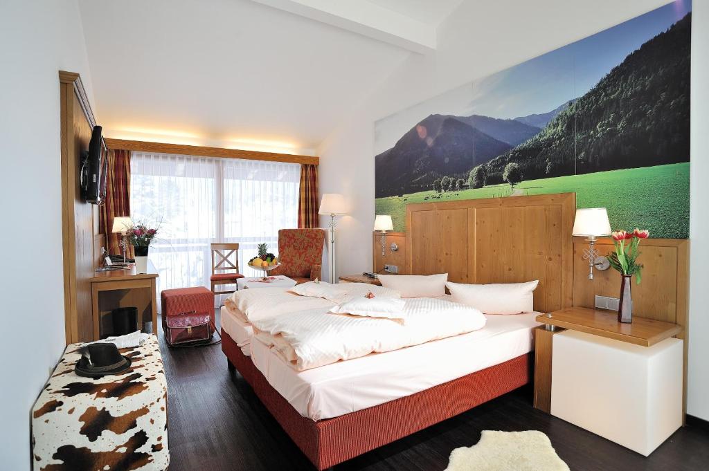 a bedroom with a large bed with a painting on the wall at Landhotel Böld Oberammergau in Oberammergau