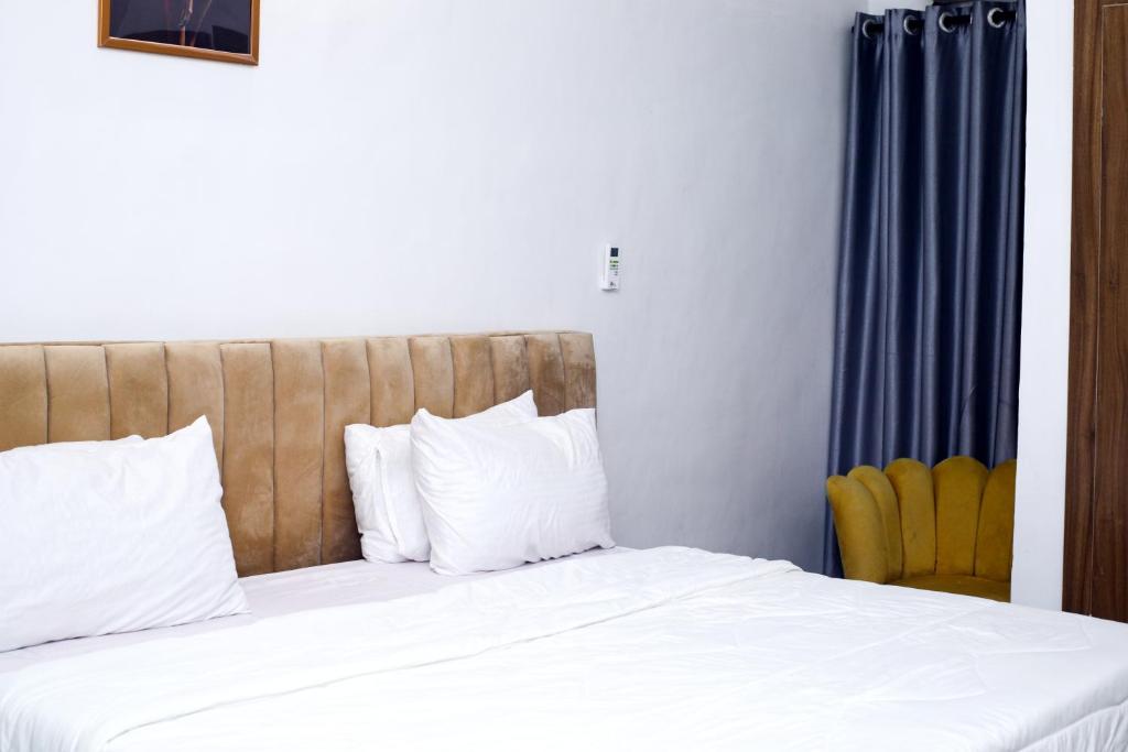 a bedroom with a bed with white sheets and a chair at Coded Hub Guest House in Lekki