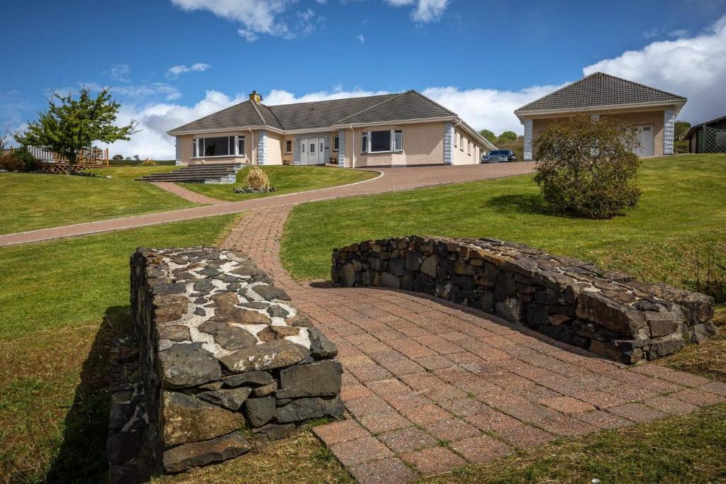 a stone retaining wall in front of a house at Loch Eyre Oasis in Kensaleyre