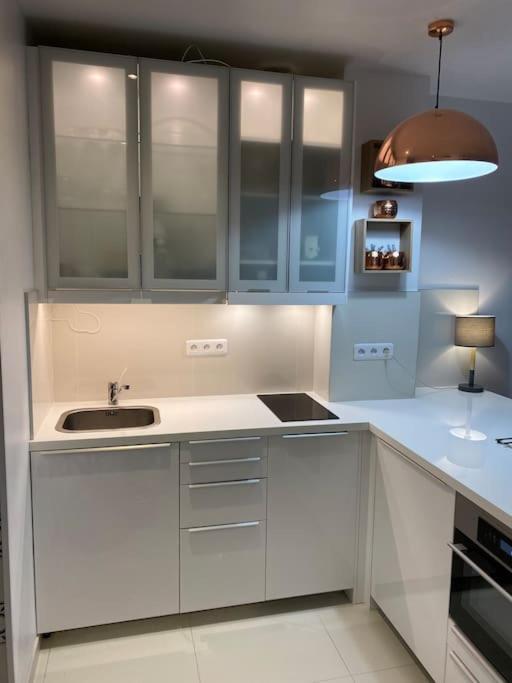 une cuisine avec des armoires blanches et un évier dans l'établissement Le fameux Montmartre, à Paris