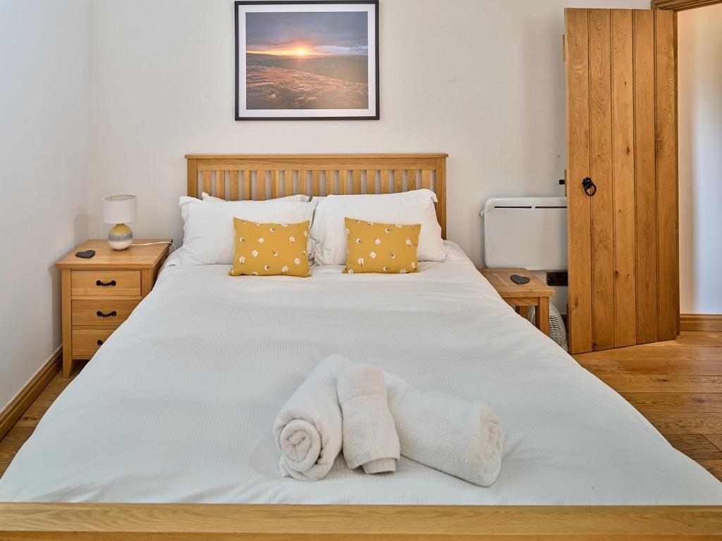 a bedroom with a white bed with towels on it at Bridge End in Langthwaite