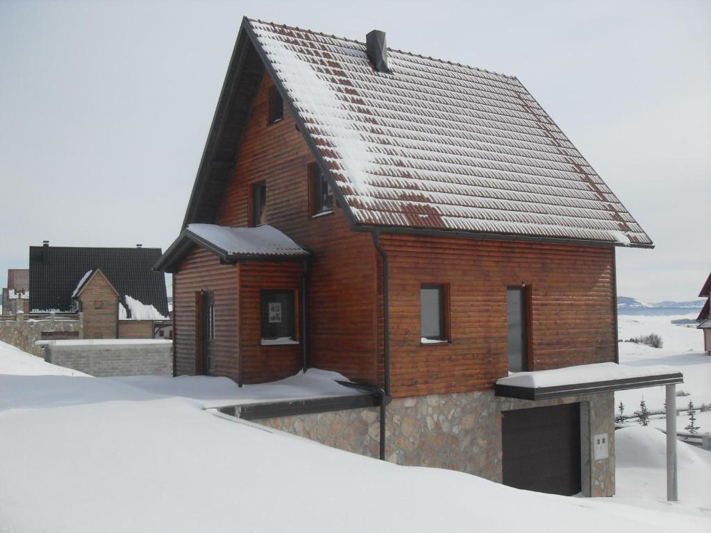 una pequeña casa de madera con nieve en el suelo en Vila Ružica en Kupres