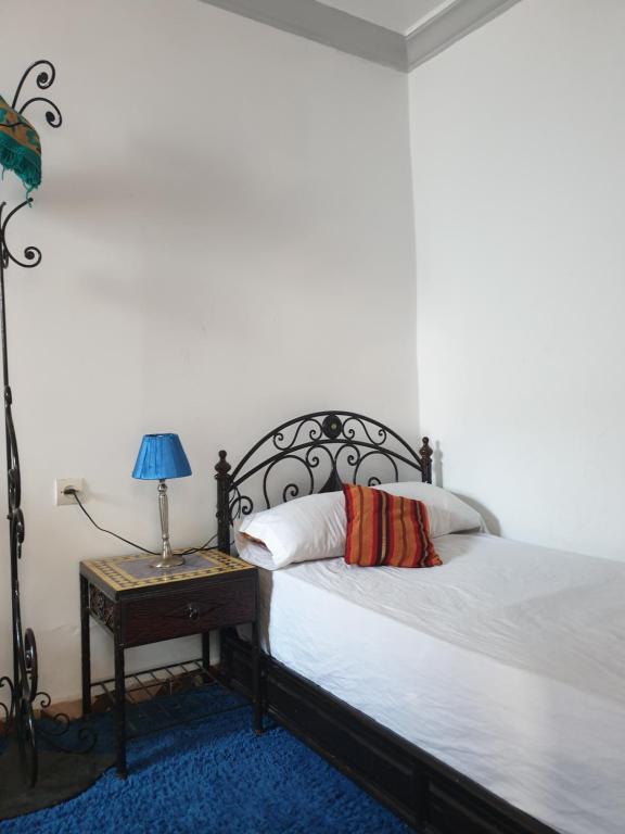 - une chambre avec un lit et une table avec une lampe dans l'établissement Blue heart, à Chefchaouen