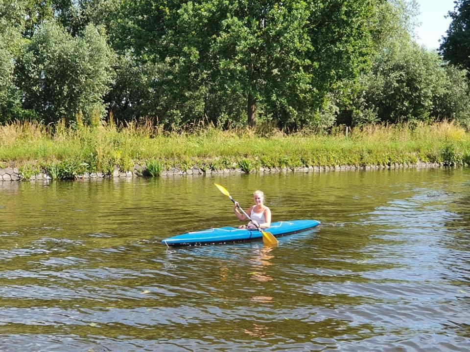 een vrouw peddelt een kajak op een rivier bij Camping de Oude Rijn in Ter Aar