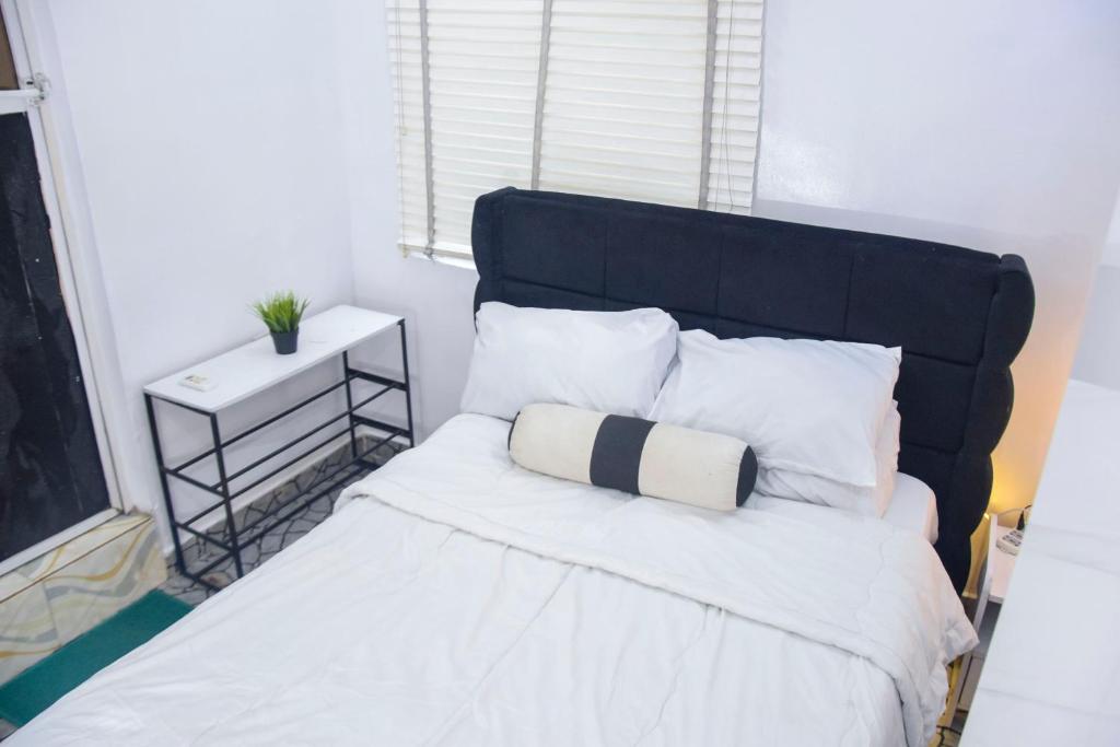a bed with a black headboard and white pillows at The Grenadines Apartment in Lagos